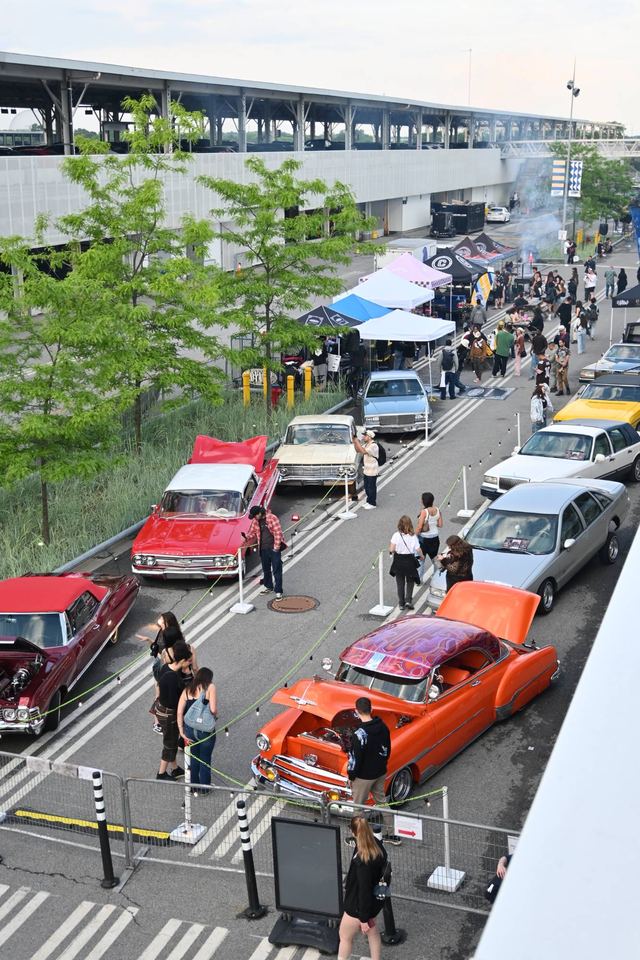 Lowriders and classic cars on display at an outdoor car show, seen from above