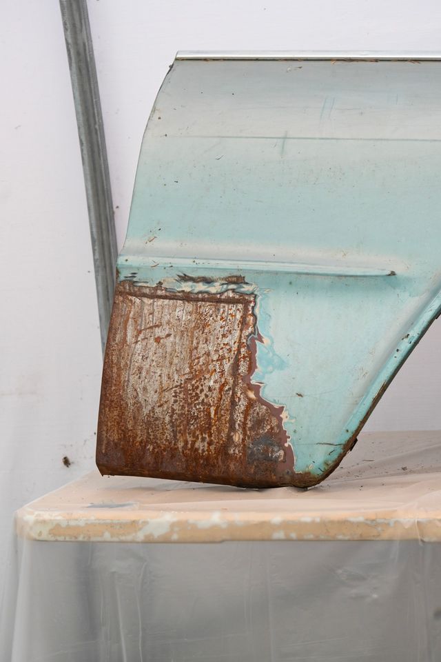 Rusted lower corner of a front fender, photographed close