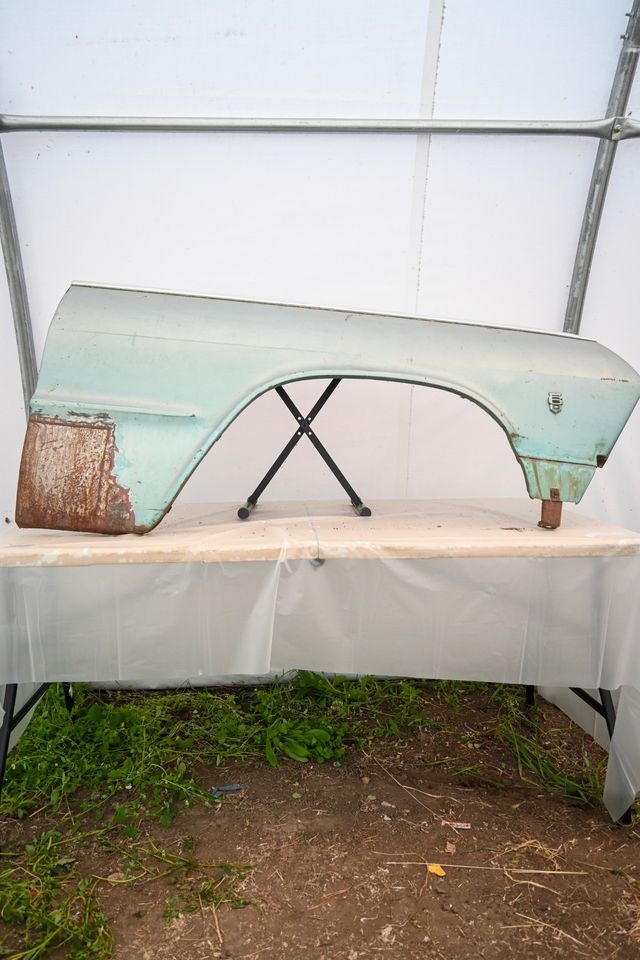 Front fender set up on a table inside a portable white backdrop tent, outdoors