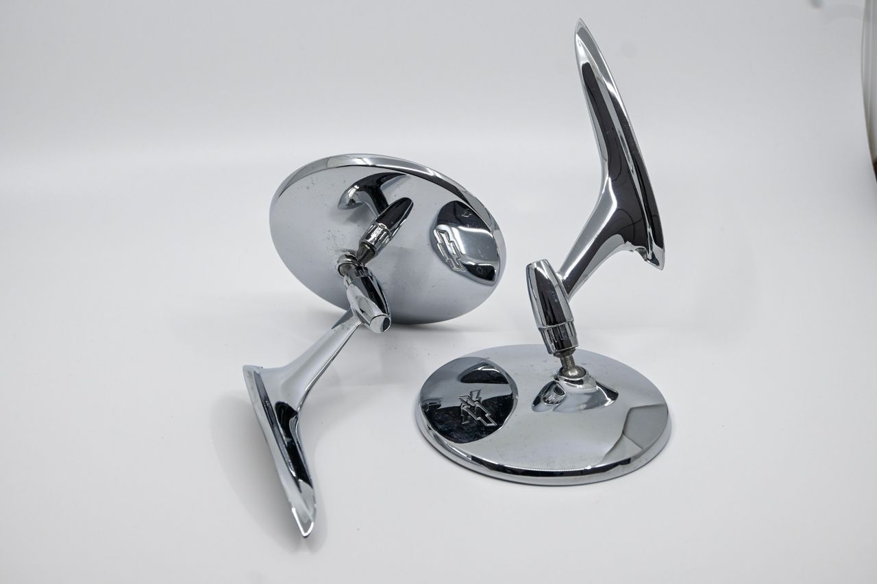 Pair of chrome Chevrolet side mirrors photographed on a white lightbox background