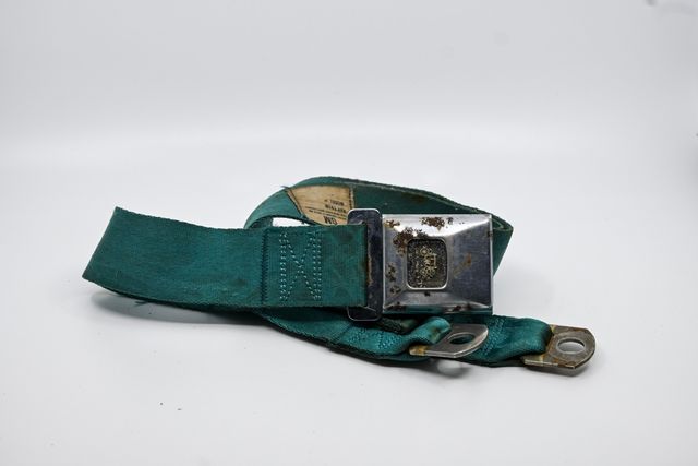 Green GM lap belt with a pitted, rust-spotted chrome buckle