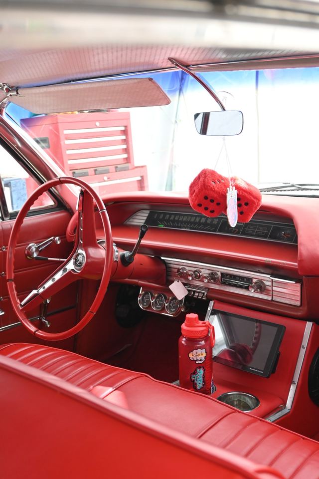 Red interior of a classic Chevrolet Impala: dash, steering wheel and bench seat