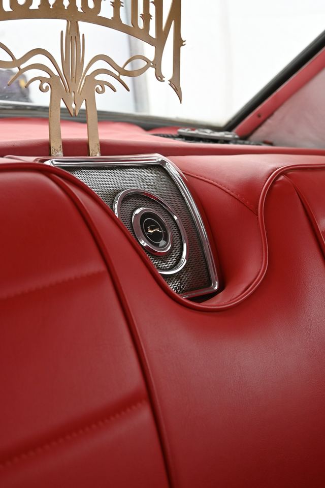 Chrome rear speaker grille set into red vinyl upholstery