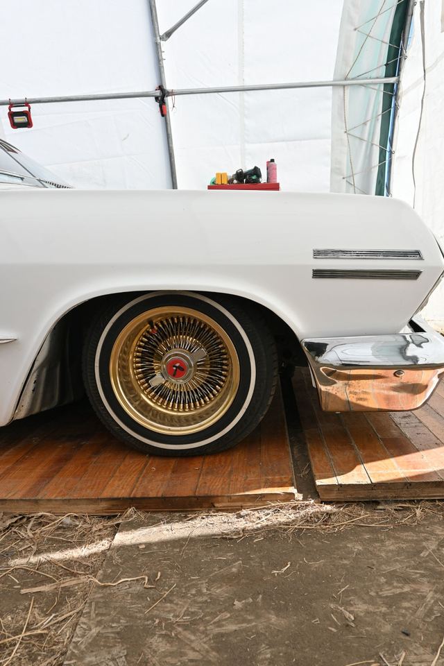 Gold wire wheel and whitewall tire on a white classic Chevrolet